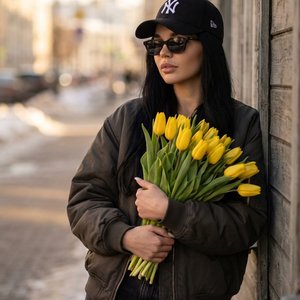 1. Используй лицо и внешность человека с загруженного входящего фото, сохрани 100% сходство, естественные пропорции и индивидуальные черты без изменений. Создай фотореалистичный вертикальный портрет в той же одежде, что на предыдущем фото: черная бейсболк