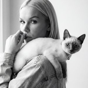 НЕ МЕНЯЯ Черты лица черно-белая фотореалистичная портретная фотография в вертикальном формате 2:3, стиль пленочного скана (SOFT FILM LOOK) ЛЁГКОЕ ЗЕРНО, НАТУРАЛЬНАЯ КОЖА БЕЗ ГЛЯНЦЕВОЙ РЕТУШИ. КРУПНЫЙ ПЛАН ПО ПЛЕЧИ/ТОРС: МОЛОДАЯ ЖЕНЩИНА СЛЕВА В КАДРЕ, ПОВЕ
