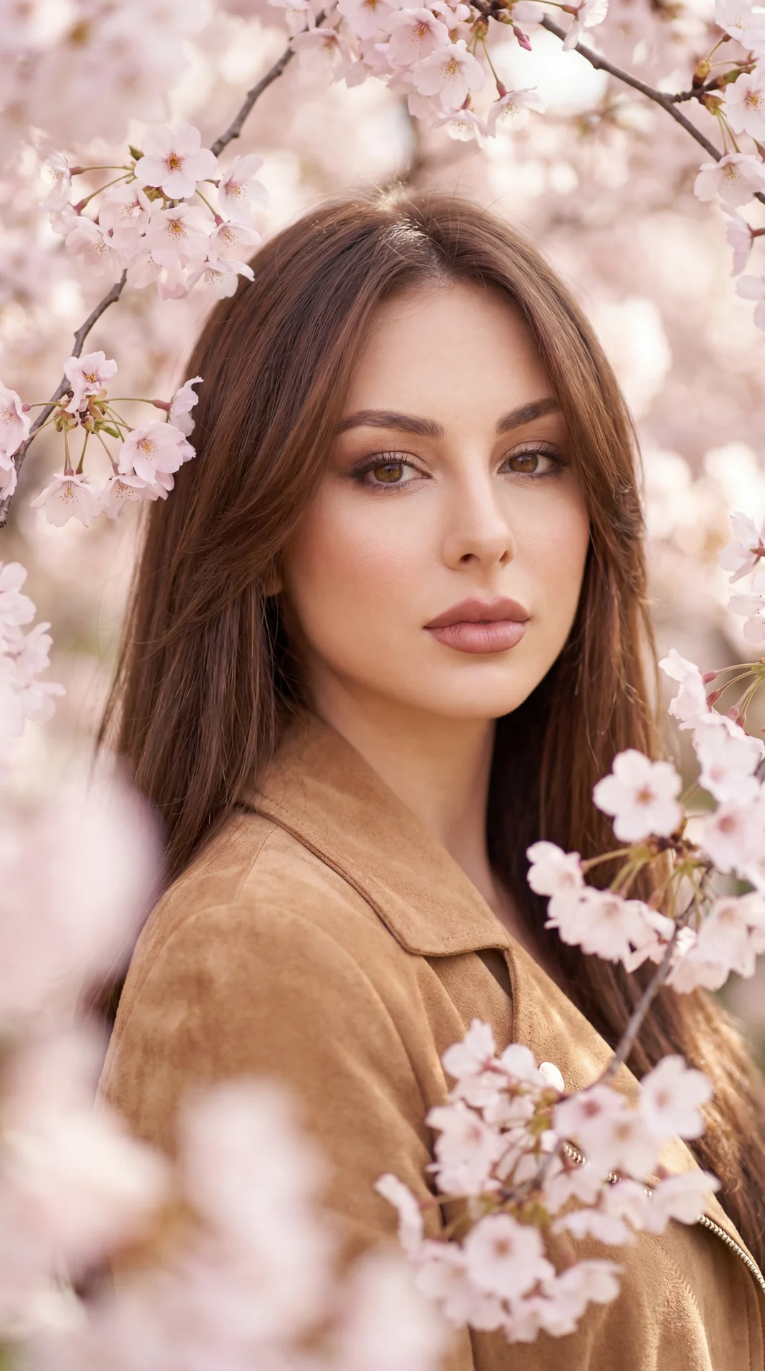 Professional close-up portrait of a woman among blooming cherry blossoms, shot on a full-frame camera with an 85mm lens at f/1.8, ISO 100, 1/500s; eye-level, straight-on angle, portrait orientation, center-framed; pose: shoulders relaxed and facing the ca
