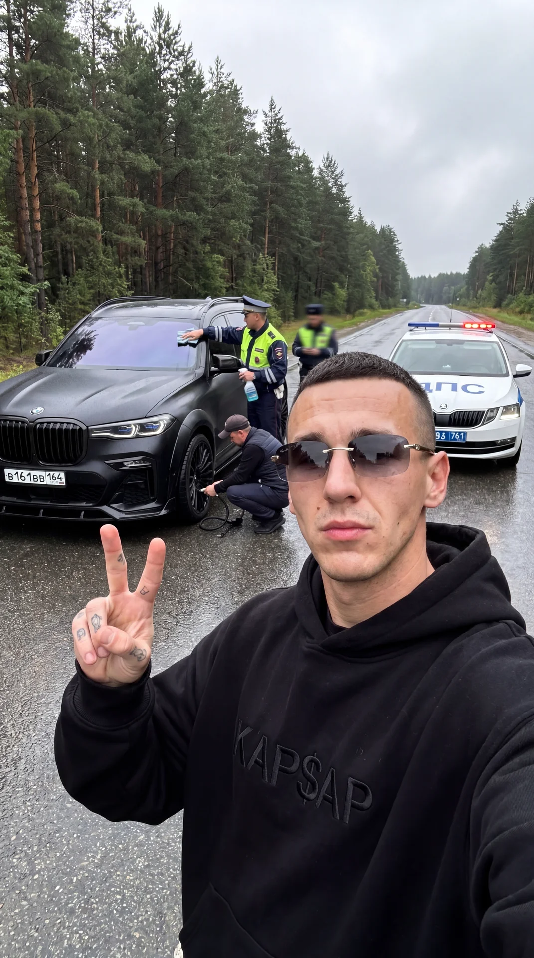 Не меняя внешности парня с фото создай селфи кадр на фронтальную камеру iPhone, 
сцена происходит в пасмурную погоду на мокрой асфальтированной трассе сразу после дождя, небо отличается серостью, влажный воздух,по обе стороны густой хвойный лес и линная п