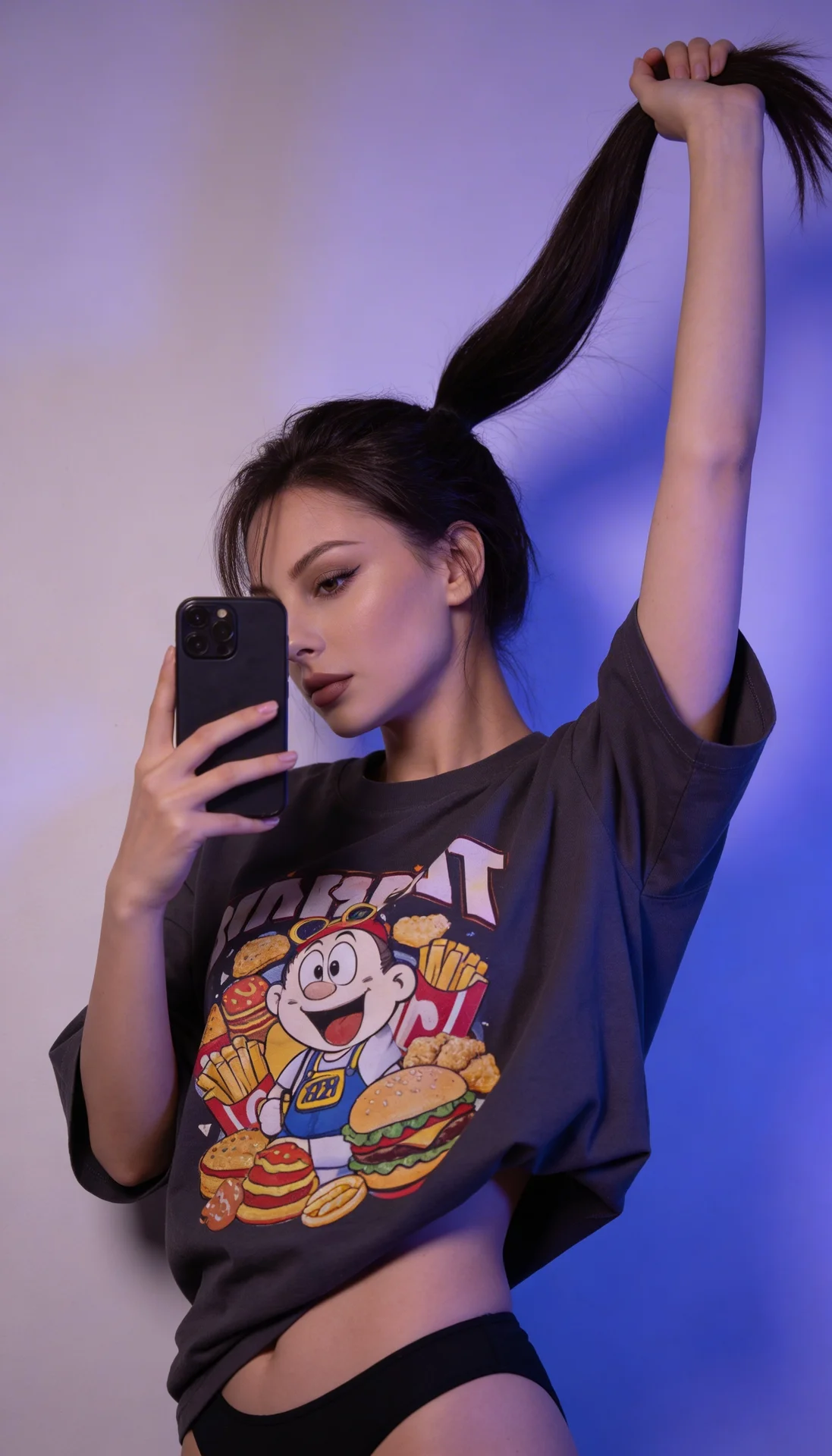 A girl is standing indoors against a plain wall illuminated with soft purple-blue lighting, giving the photo a moody, futuristic atmosphere. She is holding a smartphone in her right hand in front of her face, partially covering it, while her left arm is r