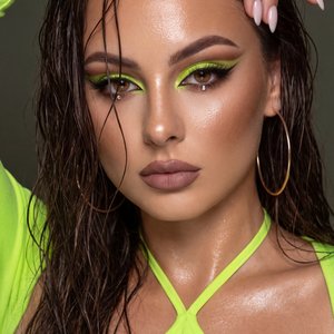 A girl captured in a high-end, professional beauty editorial close-up portrait with a "wet" and glamorous aesthetic.

Pose and Body Language: The frame captures her from the chest up. She is posing with her left arm (viewer's right) raised high above her 