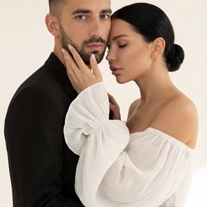 Использовать входящее фото только как источник лиц, кожи, волос и пропорций людей. Полностью и строго воссоздать сцену как на референсе без изменений. Вертикальный формат 9:16, фотореализм, fashion editorial стиль.

Мужчина и женщина позируют в студии на 