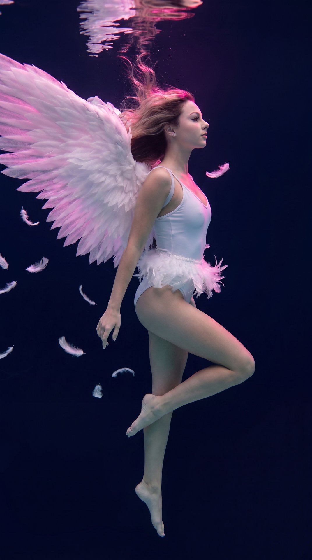 Don't change my facial feature, an ethereal underwater shot of a beautiful young stunning woman appearing as a celestial angel, floating weightlessly suspended mid-water against a dark, deep navy-blue abyss. Her long, wavy light hair drifts elegantly upwa