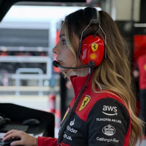 Ultra realistic cinematic
Formula 1 paddock video of the woman from the reference image inside the Ferrari F1 garage during a live qualifying session. She is wearing a red Ferrari team headset with microphone while watching the race intensely. Realistic S