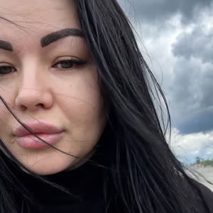 Девушка опускает глаза вниз и ветер развивает волосы