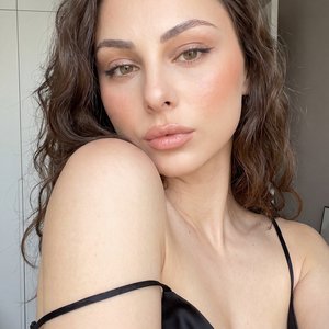 Raw candid smartphone selfie, hyper-realistic, indistinguishable from a real life photo, extremely high detailed, true-to-life skin texture, natural pores, unedited amateur mobile photography. Tight close-up front-facing camera selfie shot. The right arm 