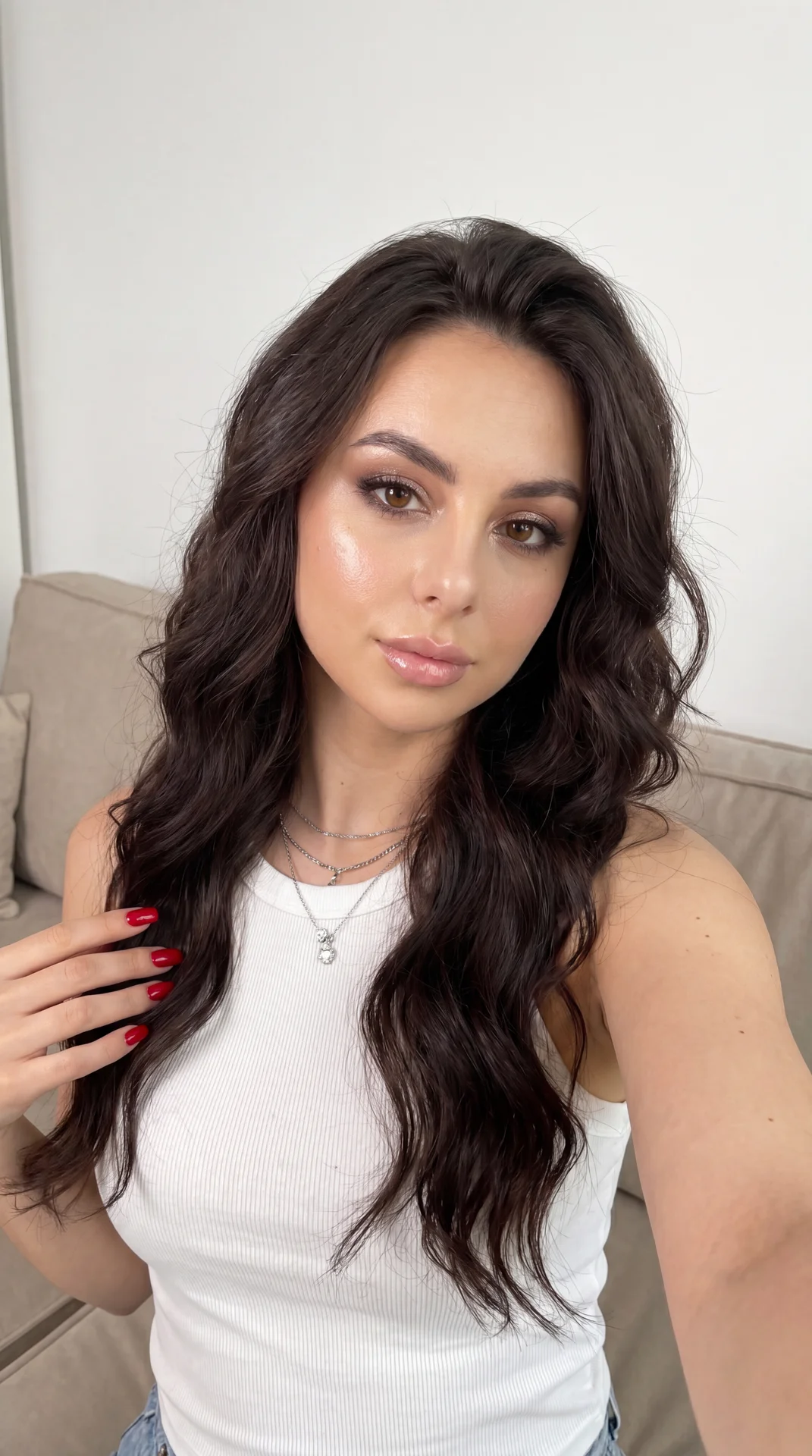 Raw photo, hyper-realistic, indistinguishable from a real photograph, ultra-high detailing, 8k resolution. Close-up first-person selfie perspective, arm extended out of frame, no phone visible. Indoor on a beige couch against a clean white wall, cozy mini