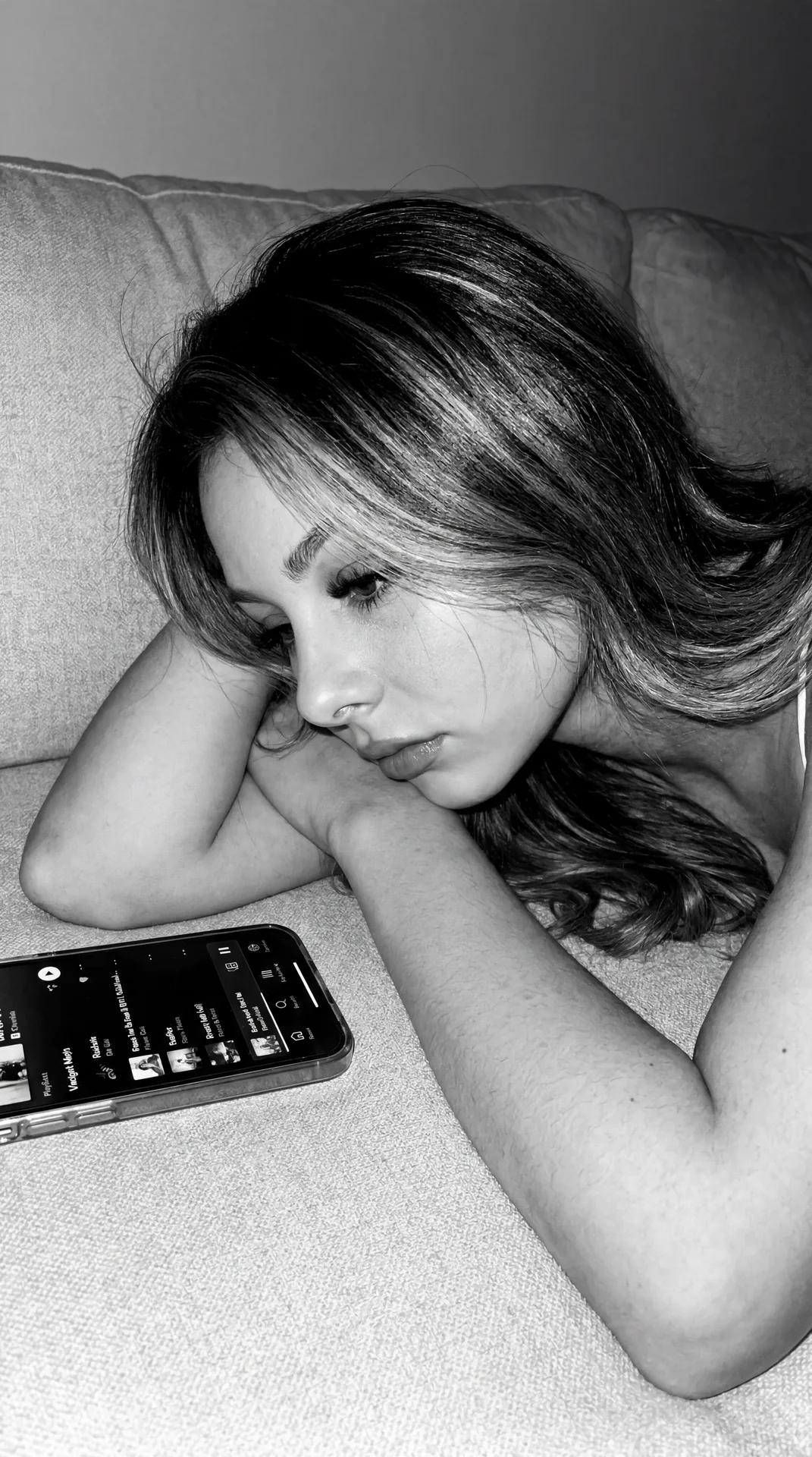 Authentic Tumblr / indie sleeze aesthetic with monochrome black-and-white tones, harsh direct flash, visible grain, soft blur, realistic digital noise, and low-quality early iPhone camera feel.

Girl lying quietly on a soft textured couch or bed at night,