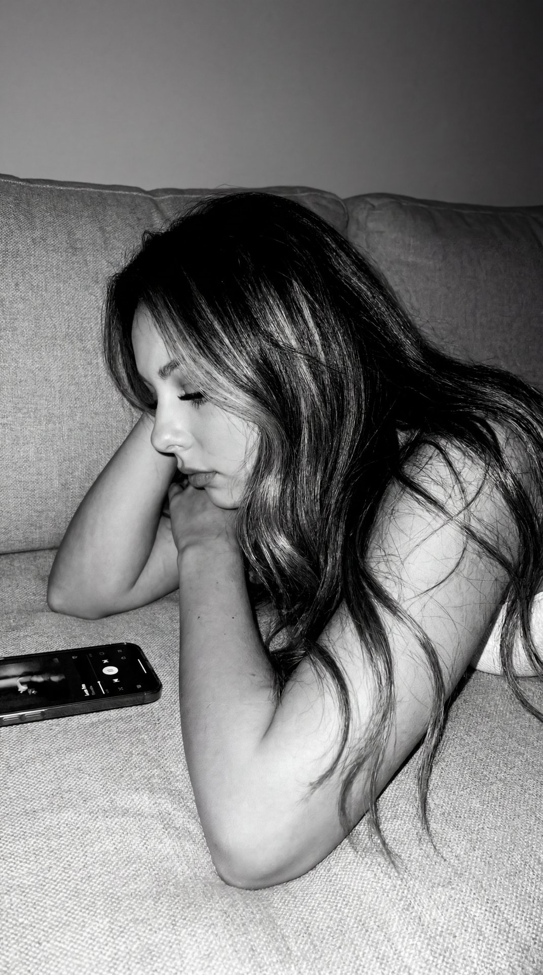 Authentic Tumblr / indie sleeze aesthetic with monochrome black-and-white tones, harsh direct flash, visible grain, soft blur, realistic digital noise, and low-quality early iPhone camera feel.

Girl lying quietly on a soft textured couch or bed at night,
