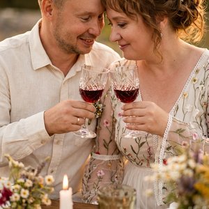 Close-up shot from a slightly elevated high angle of a romantic couple in elegant bohemian wedding attire during an intimate toast moment.

Strictly use the EXACT faces, head poses, expressions, skin texture, hair details, eye color, lip shape, proportion