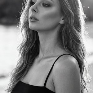 A girl — vertical medium‑close portrait (upper chest to crown), camera at eye level in a three‑quarter profile; head slightly tilted back and turned toward camera‑left, chin lifted, gaze upward toward the horizon, mouth closed with relaxed lips, hands out
