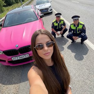Фотореалистичный вертикальный снимок селфи (9:16), сделанный на смартфоне с широкоугольной фронтальной камерой (24мм).
Молодая девушка из первого прикрепленного фото делает селфи на шоссе в солнцезащитных прямоугольных очках. Волосы шоколадные длинные по 