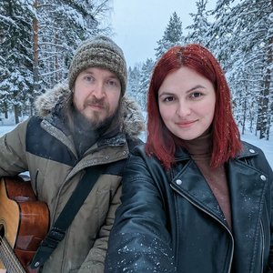 Реалистичное селфи от первого лица (POV), снятое с вытянутой руки, в том же одежда что и на фото. Крупный план. Девушка с легкой улыбкой позирует рядом с исполнителем Егором Летовым Локация:тайга зимой  фотореализм, высокое разрешение 8k.