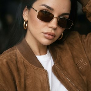 Do not change the face, facial features, body proportions, or eye color. Preserve the exact identity from the reference photo 100%. Vogue-style editorial portrait. Film grain texture, subtle analog noise, slight haze, cinematic raw feeling. Soft film filt