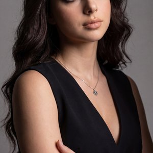 Professional studio beauty portrait, vertical tight medium close-up (chest-up), eye-level camera, three-quarter view with torso angled about 30° toward the right side of frame; head slightly tilted back and toward camera, gaze lifted off-camera to the upp