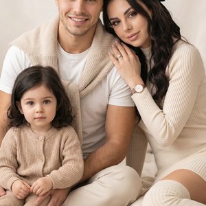 /img A real photograph, hyper-realistic, indistinguishable from a live photo, high detail, aspect ratio 9:16. A family portrait, shot with a professional camera, medium shot at eye level, depicting three people on a light-colored blanket against a soft, b