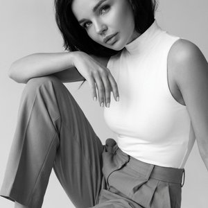 Use the face from the reference photo and preserve identity exactly without altering facial structure. Photorealistic 8K fashion editorial image. The girl’s skin is smooth and flawless, natural and real with visible pores and soft matte glow, lips closed,