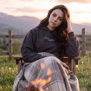 Hyper-realistic authentic raw photograph, completely indistinguishable from reality, unretouched lifestyle capture, zero CGI look. Beautiful spring sunset at a mountain cabin yard; warm campfire with glowing embers in the soft-focus foreground; subject se