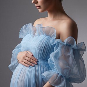 Professional studio fashion portrait, side-profile three-quarter shot at eye level (camera perpendicular), center-framed on a seamless gray backdrop; soft diffused key light front-left with gentle rim back-right; cool clean color grade, shallow DOF, high 