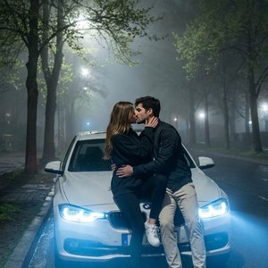 Используй лица с моей референс-фотографии (face reference), сохрани узнаваемость на 100% : не меняй овал лица , форму носа , форму бровей, губы, цвет глаз и цвет волос.Фотореалистичный полный рост.Ночной туманный городской парк, высокие деревья с весенним