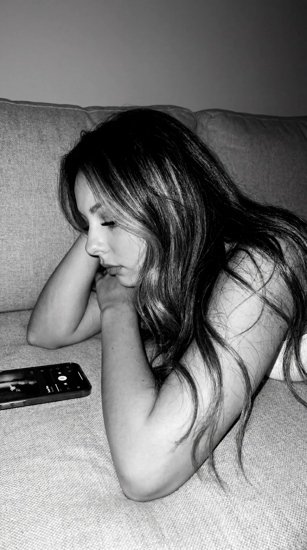 Authentic Tumblr / indie sleeze aesthetic with monochrome black-and-white tones, harsh direct flash, visible grain, soft blur, realistic digital noise, and low-quality early iPhone camera feel.

Girl lying quietly on a soft textured couch or bed at night,