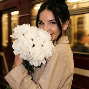 СТРОГО сохранить внешность девушки с фото 1:1 — лицо, цвет волос, пропорции без изменений. Фото — эталон. Формат 9:16. Крупный портрет по плечи: кадр от макушки до середины плеч, корпус ниже груди строго вне кадра. Девушка стоит в метро, корпус повернут в