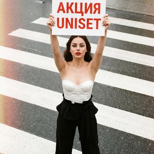 А girl on a city crosswalk, full-body long shot from a high overhead angle (professional camera, slight telephoto compression), natural daylight with soft overcast; she stands centered on bold white zebra stripes, feet hip-width apart, spine upright, shou