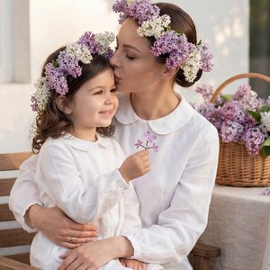 Гиперреалистичное вертикальное фото 9:16, неотличимо от живого; та же мама и та же дочь из референса, сохранить неизменными черты лица и пропорции; прическа идентичная как в референсе: у мамы гладкий низкий пучок под венком из живой сирени (сиреневые и бе