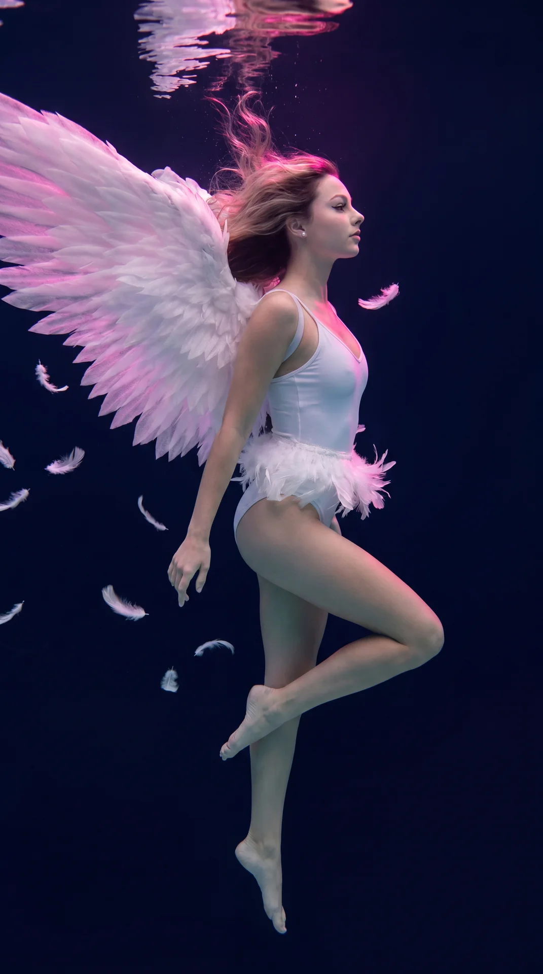 Don't change my facial feature, an ethereal underwater shot of a beautiful young stunning woman appearing as a celestial angel, floating weightlessly suspended mid-water against a dark, deep navy-blue abyss. Her long, wavy light hair drifts elegantly upwa