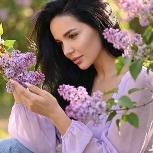 Не меняя внешности женщины с фото, перед нами предстает изящная фигура, снятая с мягкого верхнего ракурса, словно камера находится чуть выше уровня её глаз и смотрит вниз под лёгким углом. Это создаёт ощущение интимности и уязвимой нежности момента. Она с