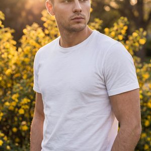Professional golden-hour outdoor изображение, medium shot (waist-up), portrait orientation, slight low-angle three-quarter view; subject framed on the right third beside lush green bushes covered with small yellow flowers; pose: torso angled slightly righ